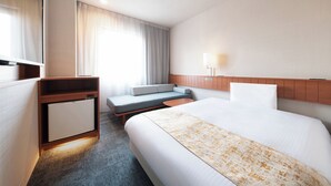 Habitación de hotel con cama, escritorio, zona de estar y televisión.