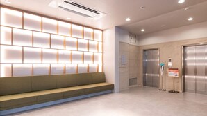 A modern lobby with a seating area, an elevator, and a wall with illuminated panels. - Vessel Inn Fukuyama Station (Fukuyama)