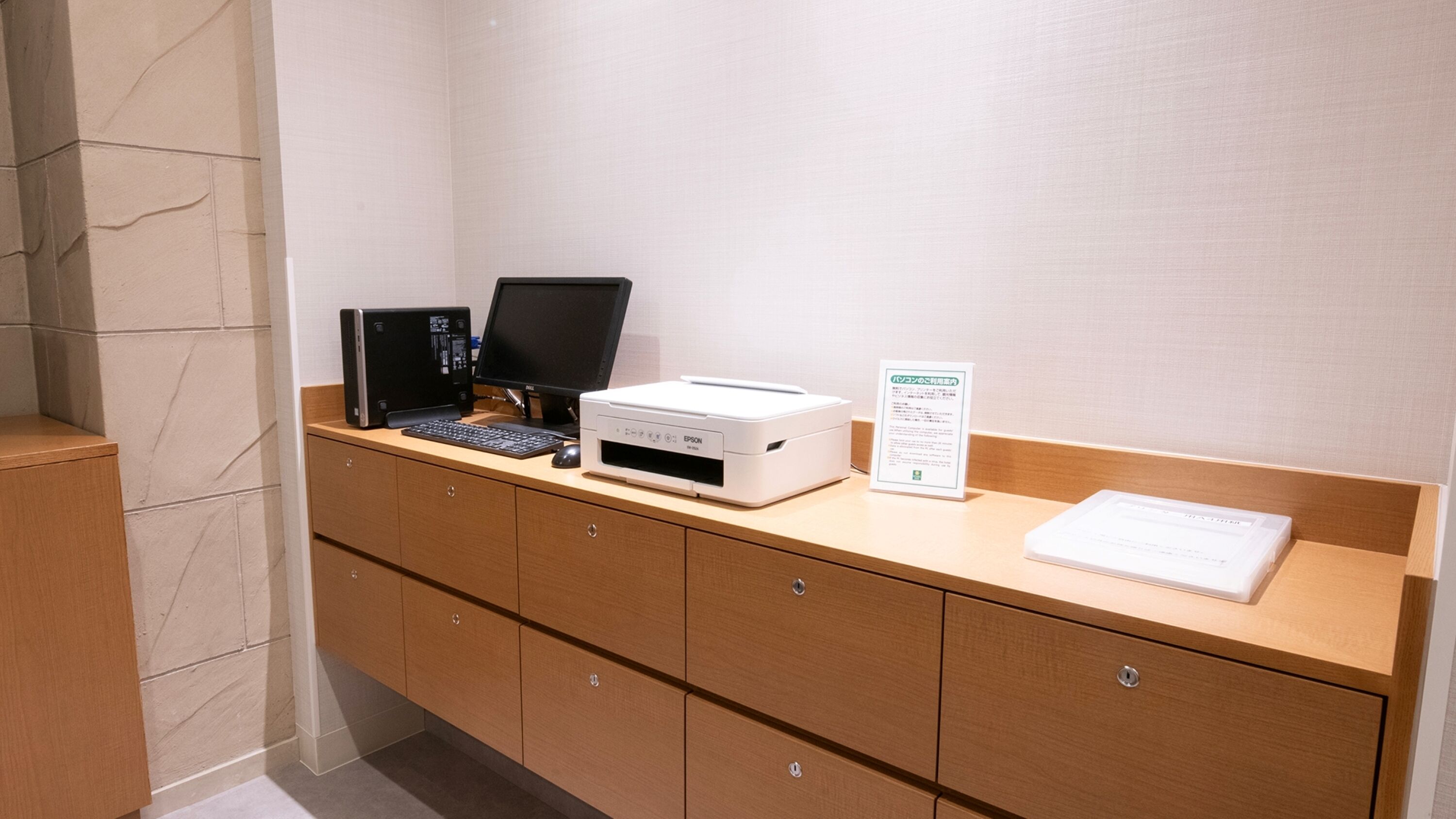 A reception desk with a computer, printer, and a sign.