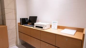 A reception desk with a computer, printer, and a sign.
