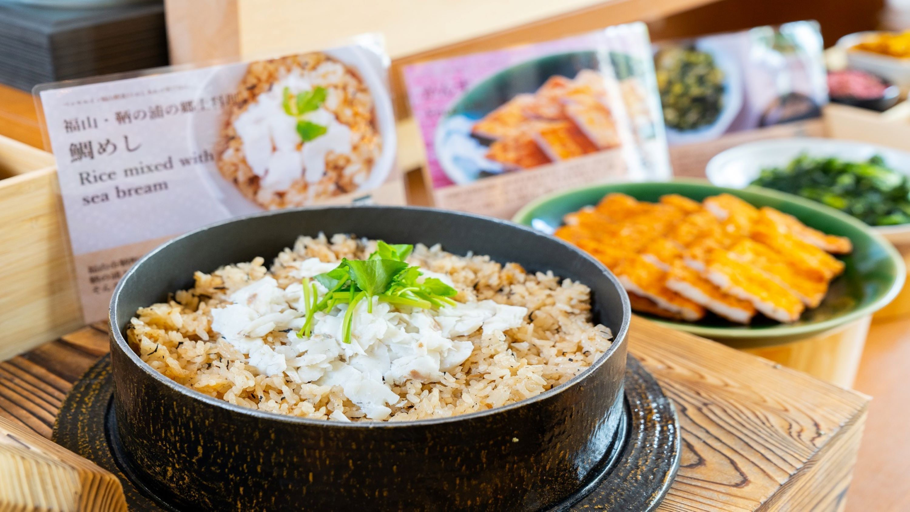 Un tazón de arroz con besugo y una guarnición de hojas verdes.
