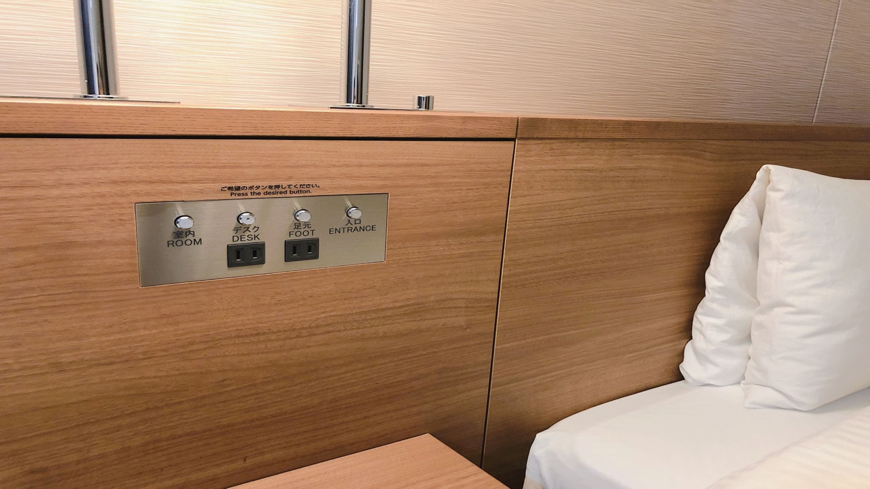 Un panel de madera con un tablero de control que tiene botones etiquetados 'ROOM', 'DESK', 'FOOT' y 'ENTRANCE'.