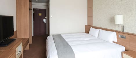 A hotel room with a bed, a TV, a desk, and a lamp.