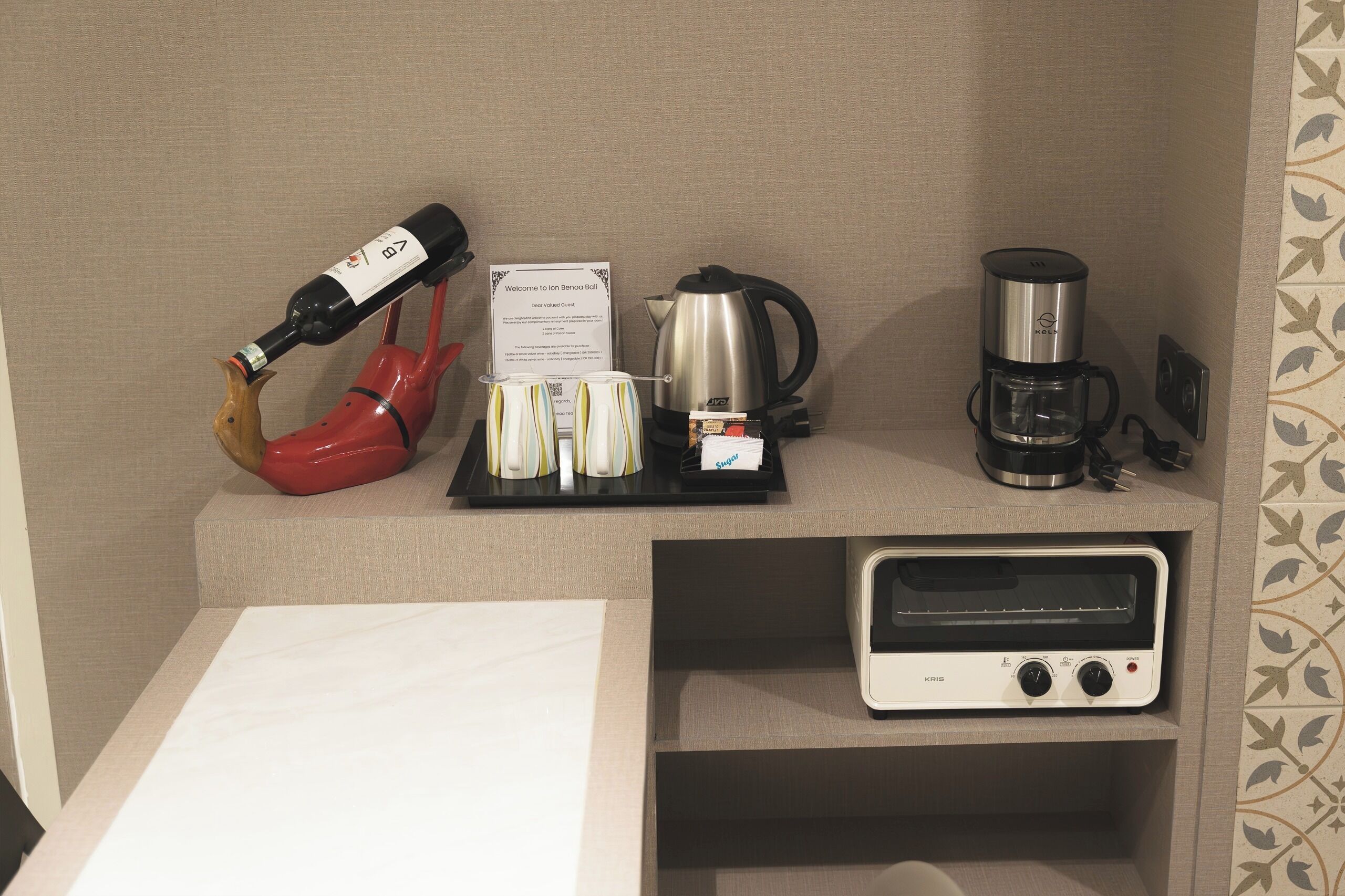 A minibar with a wine bottle, coffee maker, kettle, and a toaster.