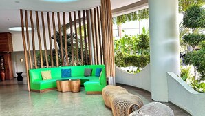 A modern lobby with a green sofa, wooden columns, and a decorative elephant statue. - Ion Bali Benoa (Nusa Dua)