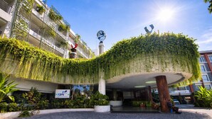 A hotel entrance with a curved green roof garden, a globe sculpture, and a sign for the hotel. - Ion Bali Benoa (Nusa Dua)