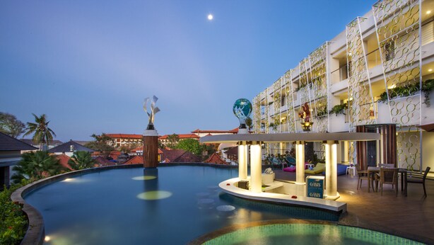 A swimming pool with a sunken area, a decorative globe, and a building with balconies and plants. - Ion Bali Benoa (Nusa Dua)