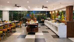 A modern restaurant with a checkered floor, round tables, and colorful chairs. - Ion Bali Benoa (Nusa Dua)