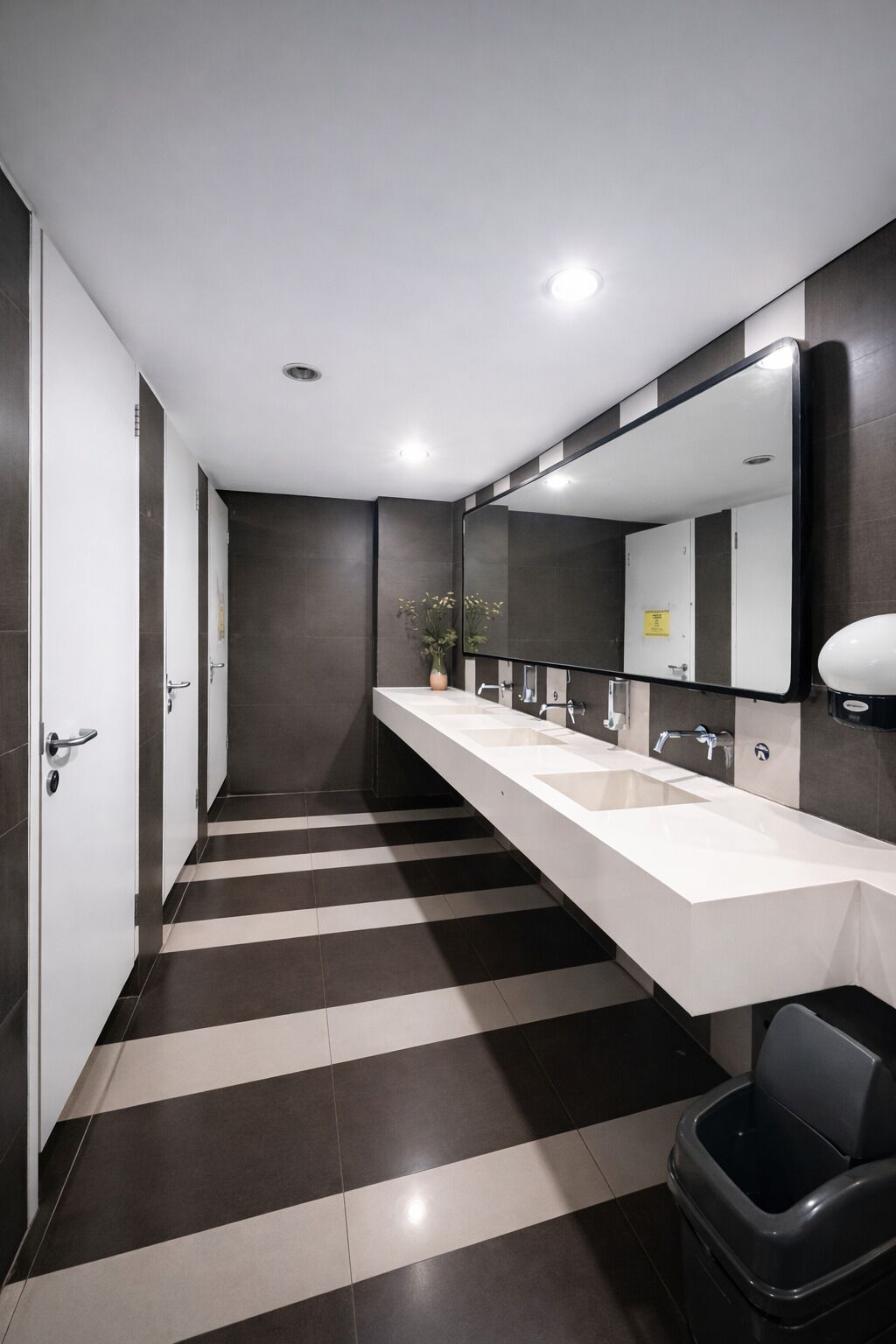 A modern bathroom with two sinks, a large mirror, and a striped floor.