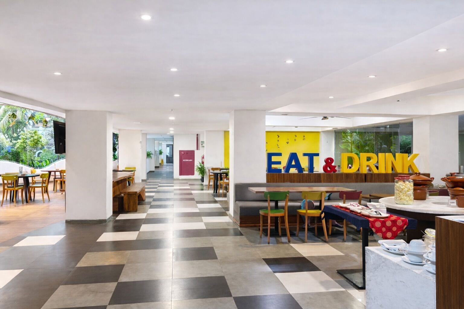 A modern dining area with a checkered floor, a central seating area, and a wall with 'EAT & DRINK' signage.