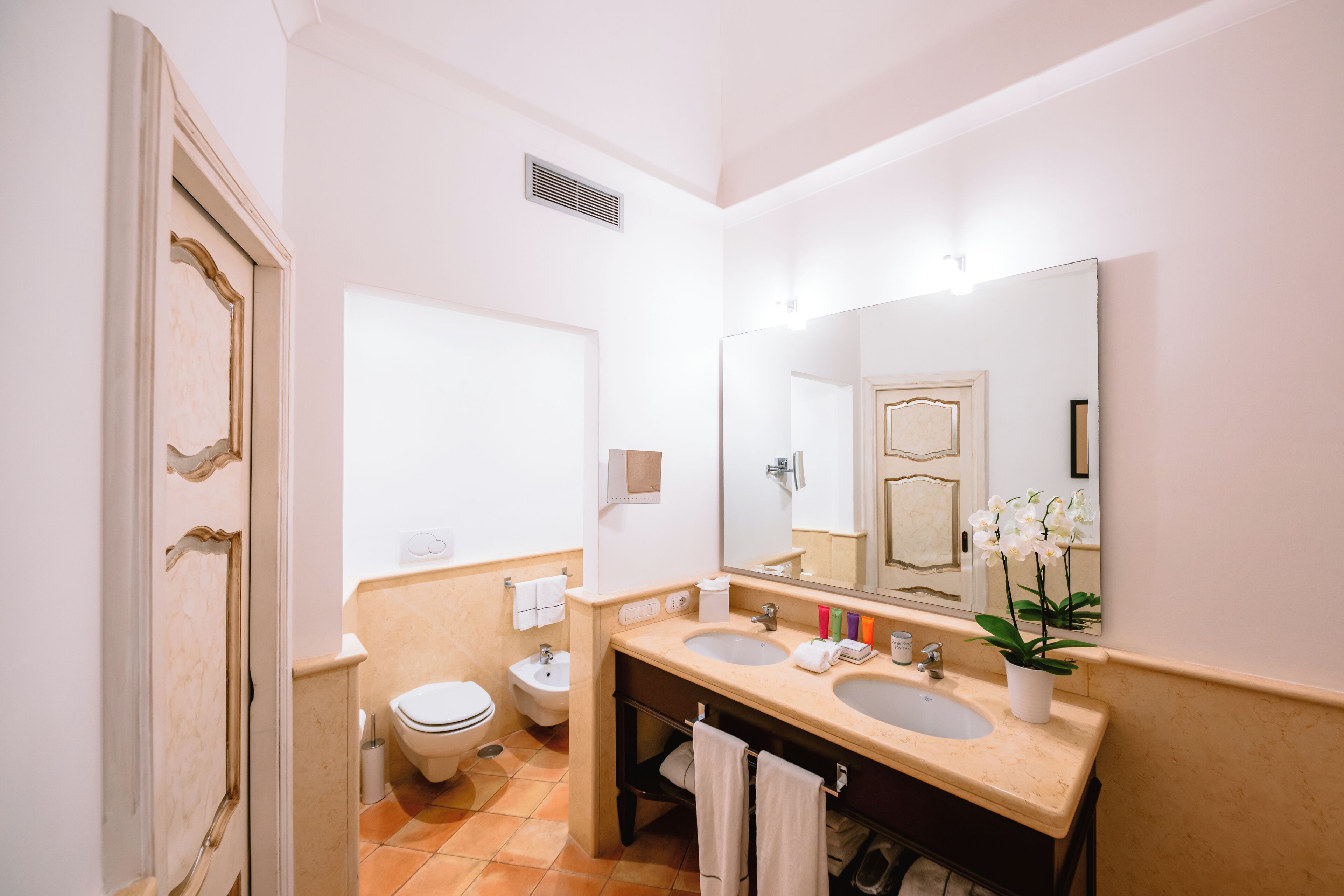 A bathroom with a double sink, a toilet, and a bidet.