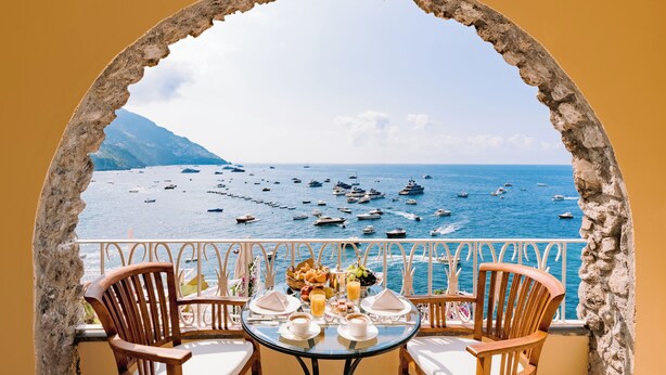 Une table dressée pour le petit-déjeuner, avec vue sur la mer et les bateaux.