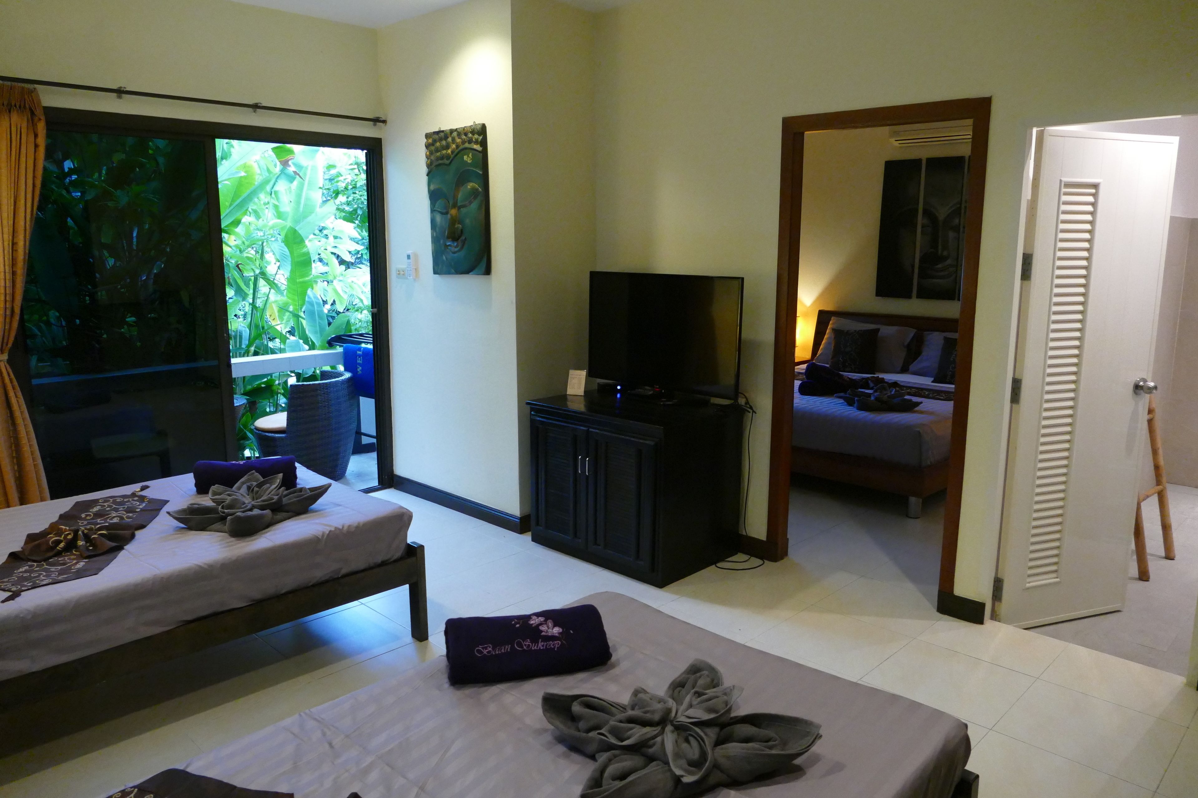 A hotel room with a bed, a TV, a desk, and a view of the outdoors.