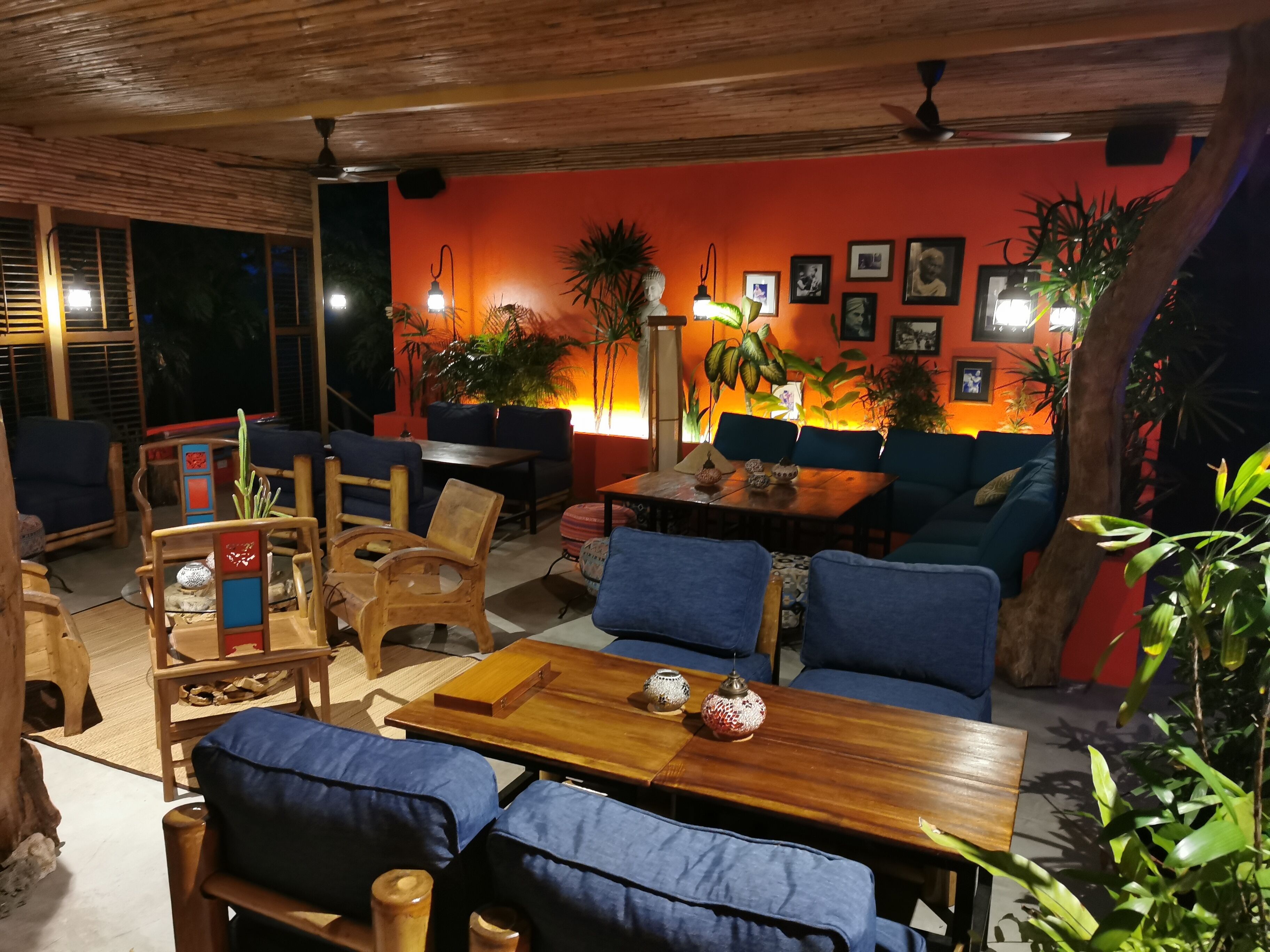 Ein gemütlicher Innenbereich mit Holzmöbeln, einem Tisch mit Dekoration und einer warmen orangefarbenen Wand mit gerahmten Bildern.