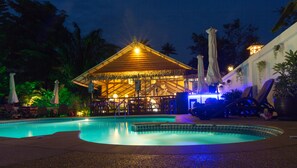 Een buitenzwembad, parasols bij het zwembad en ligstoelen