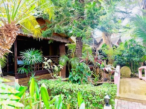 A tropical garden with a wooden structure, lush greenery, and a stone pathway. - Baan Sukreep Resort (Koh Samui)