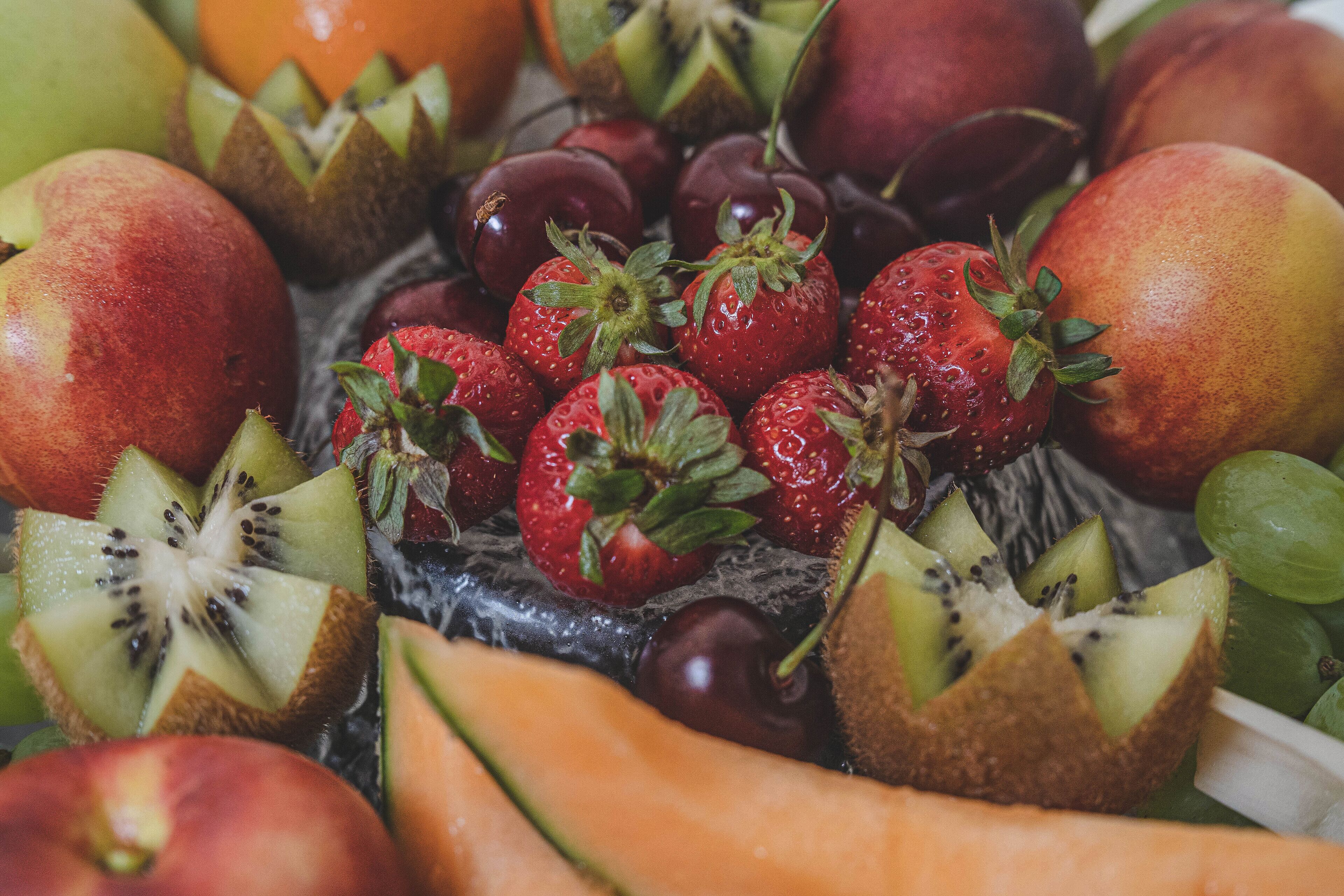 Un assortiment de fruits frais, notamment des fraises, des kiwis et des pêches.