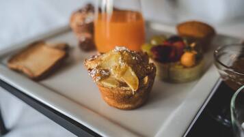 Un safata d'esmorzar amb un muffin, torrades, fruita i un got de suc d'aranja.