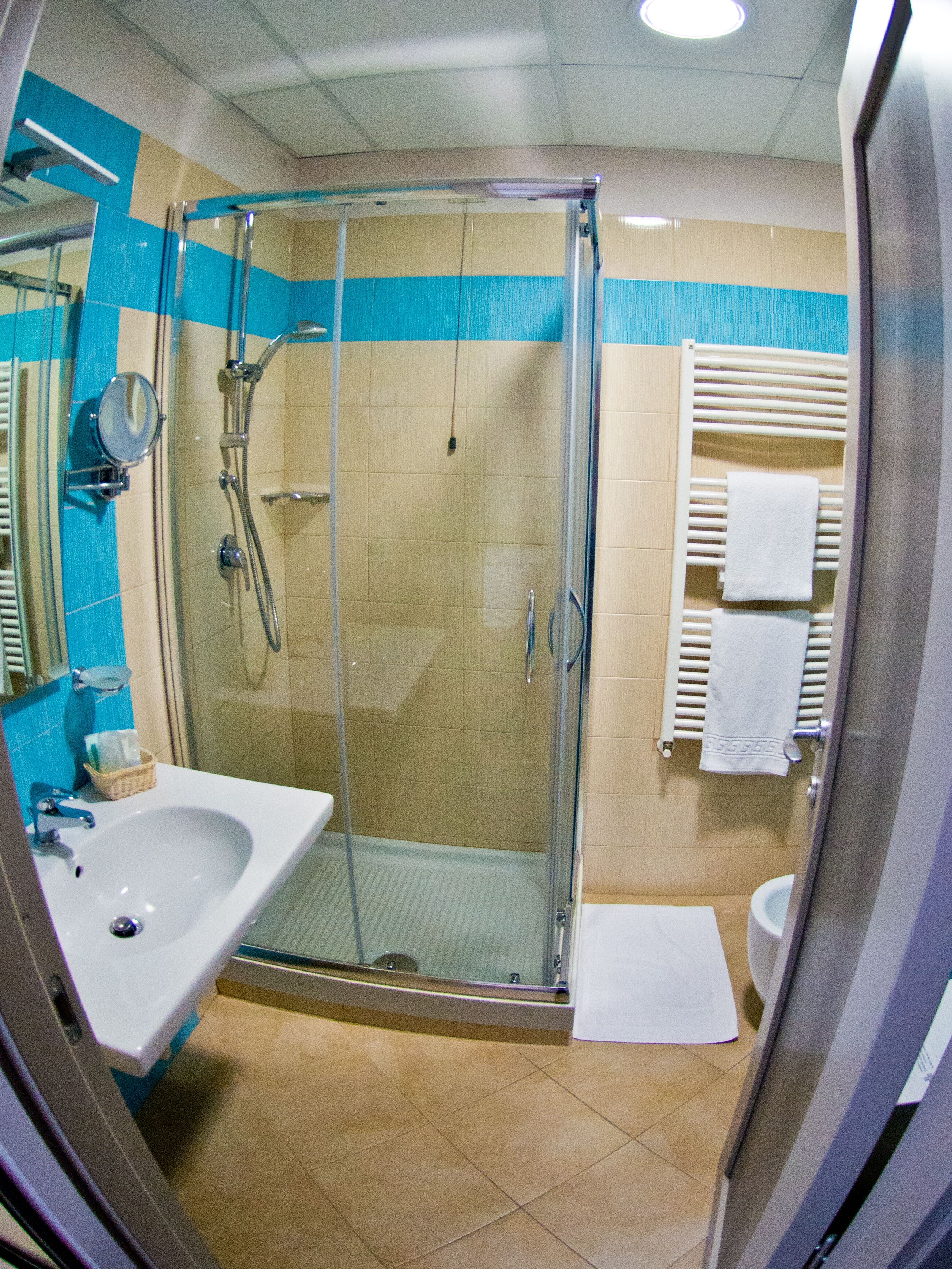 Et moderne badeværelse med en glasbrusekabine, håndvask og toilet.