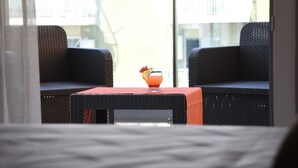 Un balcon avec des fauteuils en osier et une petite table sur laquelle se trouve une boisson.