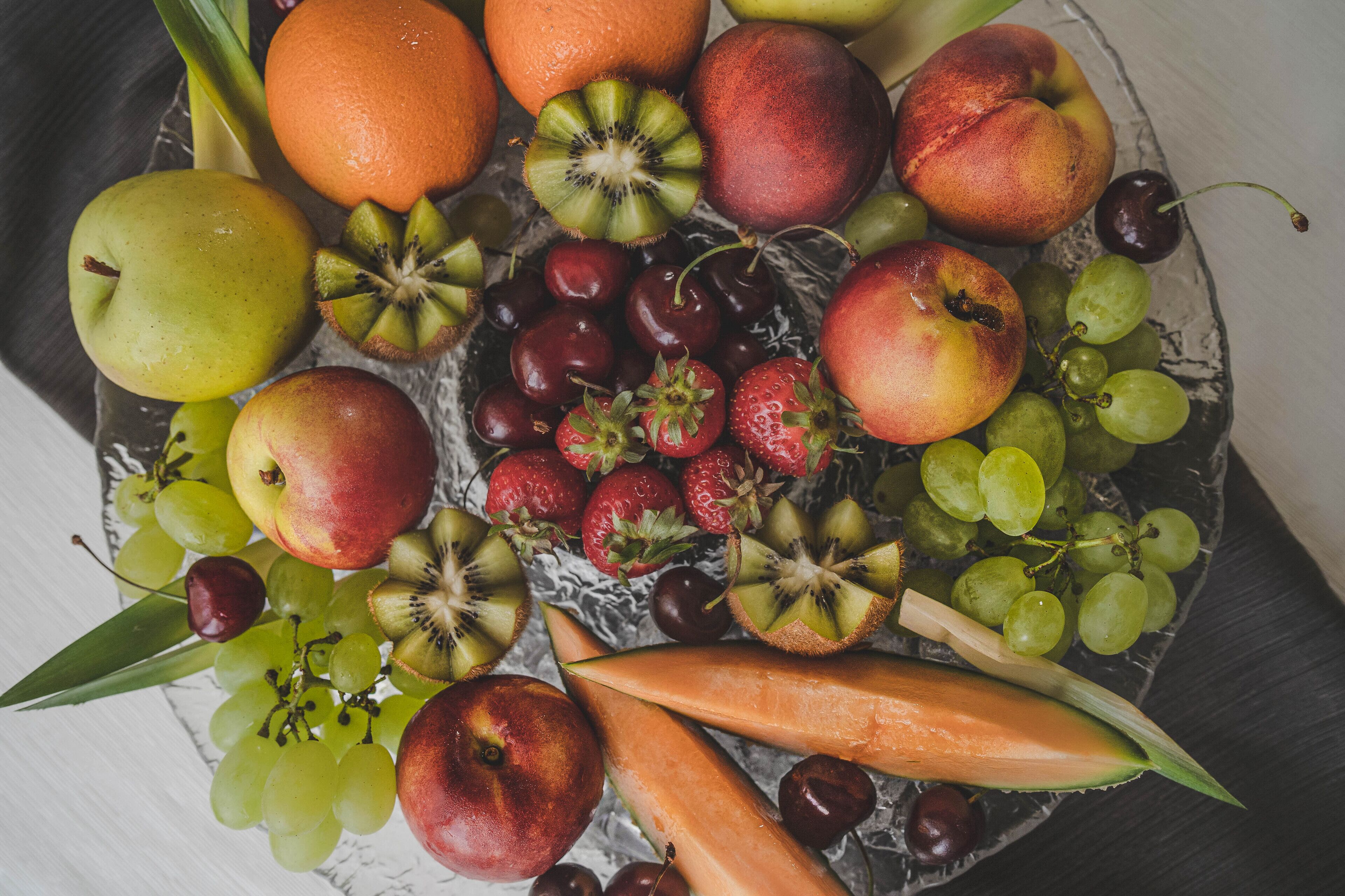 A variety of fruits including apples, oranges, grapes, and kiwis arranged on a plate.