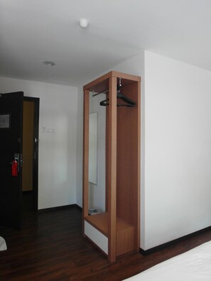 A hotel room with a wooden wardrobe, a mirror, a hanging black hanger, and a white door. - Nagoya Inn Hotel (Langkawi)