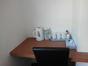 A small wooden table with a white kettle, water bottles, and a tray with white cups and a box labeled "PREMIER". - Nagoya Inn Hotel (Langkawi)