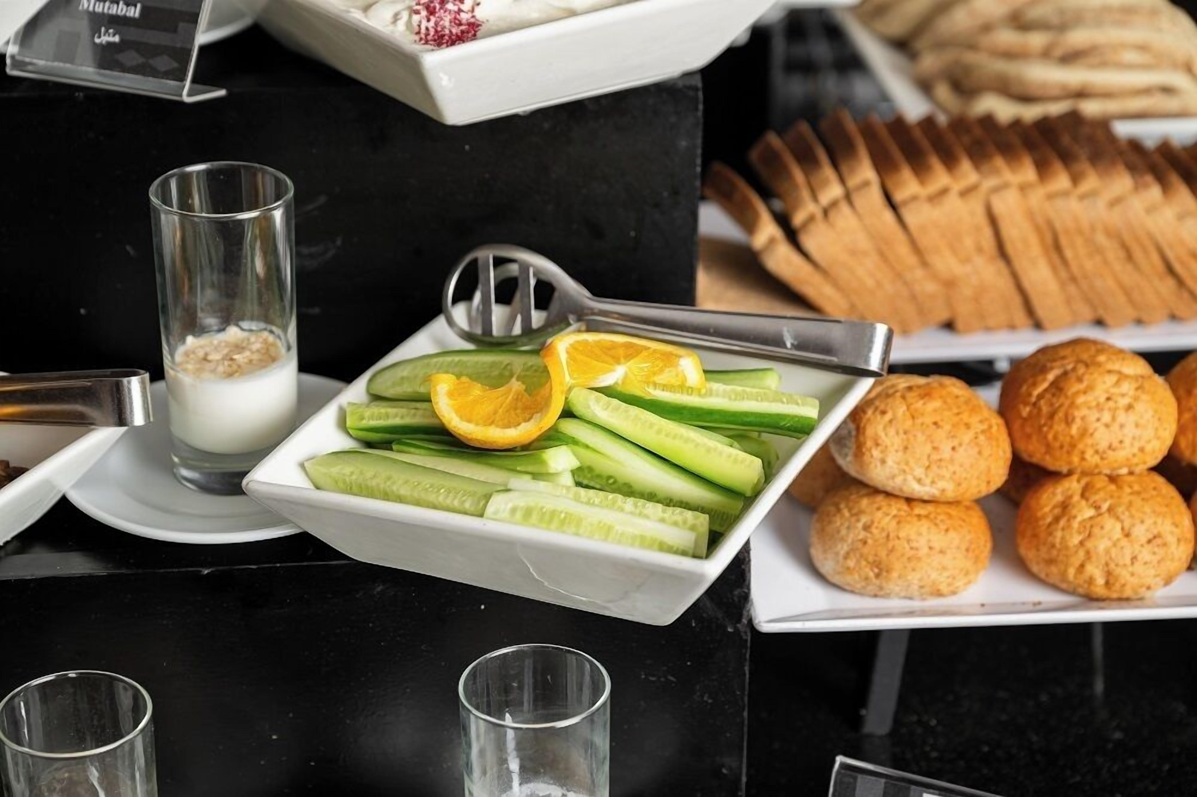 Un tavolo da buffet con fette di cetriolo, spicchi d'arancia e un bicchiere di latte.