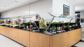 A modern buffet setup with glass display cases, a variety of food items, and decorative plants. - Elaf Bakkah Hotel (Makkah)