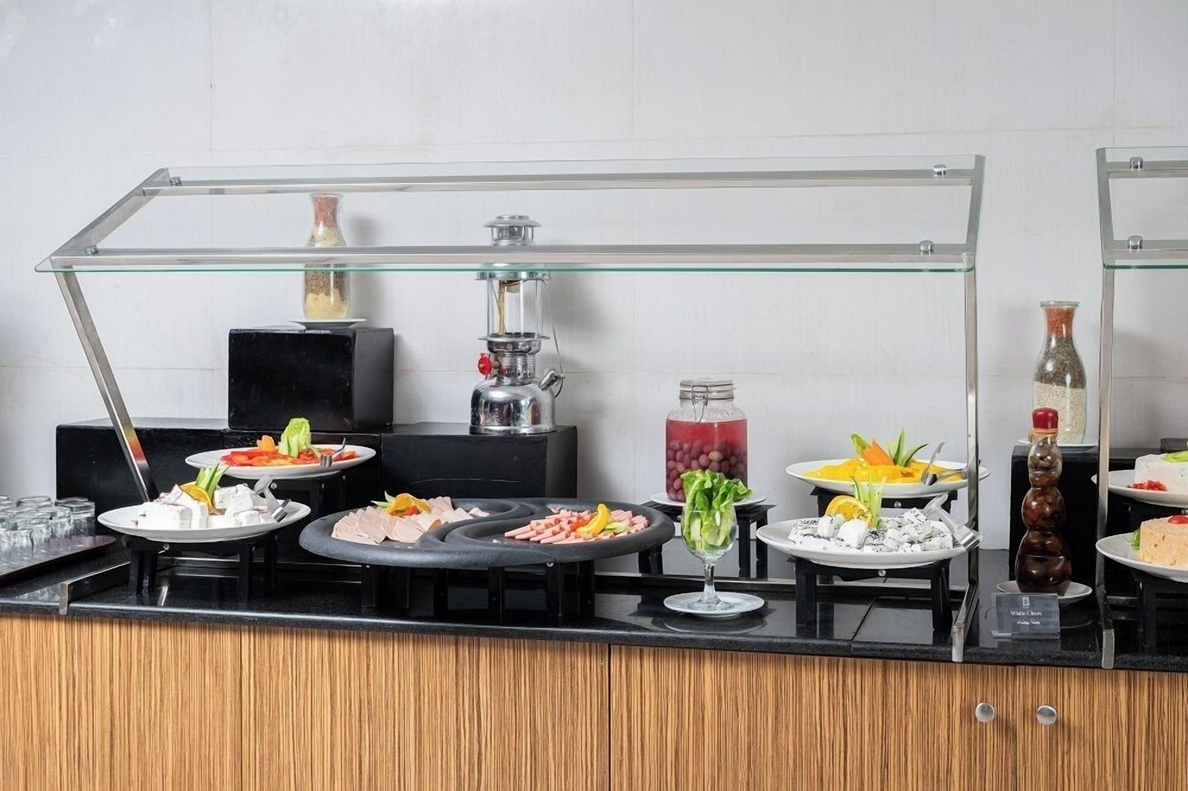 Montaje de bufé con diversos alimentos y un dispensador de bebidas.