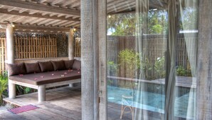 A covered outdoor seating area with a bench and a glass partition. - Les Villas Ottalia Gili Trawangan (Gili Trawangan)