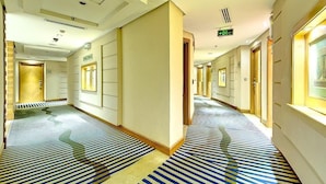 A hotel corridor with patterned carpet, doors, and a sign indicating an exit. - Hotel Prestige (Makkah)