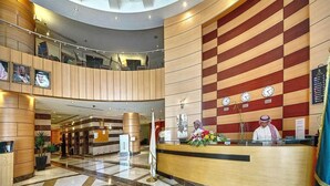 A hotel lobby with a reception desk, a check-in counter, and a seating area with a high ceiling and modern design. - Hotel Prestige (Makkah)