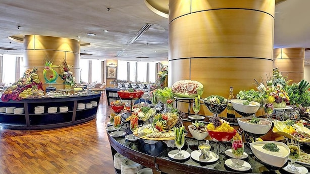 A buffet with various food items and a decorative centerpiece. - Hotel Prestige (Makkah)