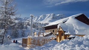 Un village de montagne enneigé, avec des bâtiments en bois et un ciel dégagé.