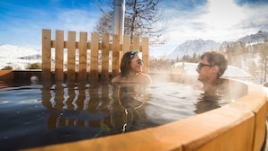Un bain à remous doté de rampes en bois, avec une chaîne de montagnes en arrière-plan.