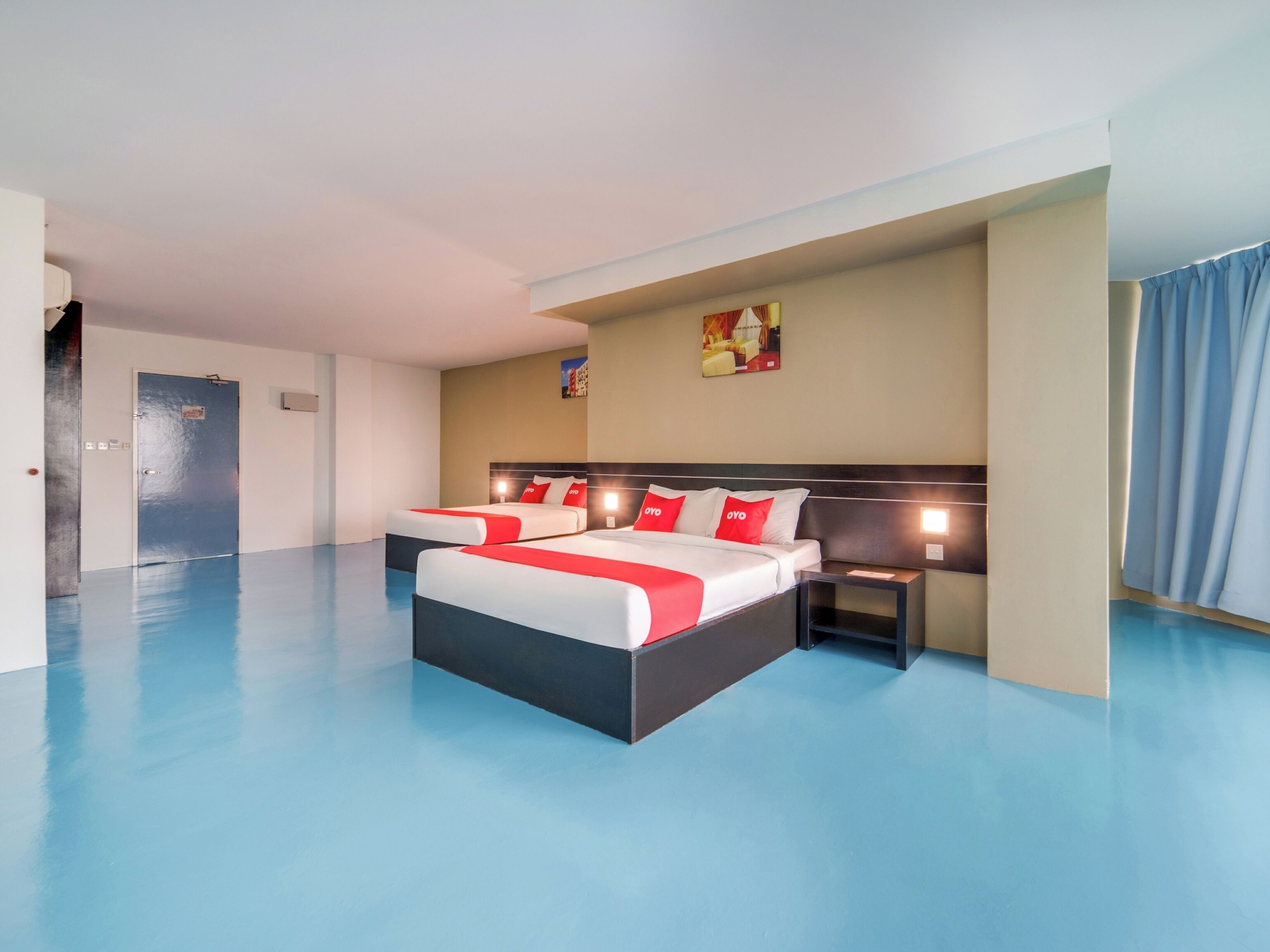 Habitació d'hotel amb un llit gran, dues taules de nit i un sòl blau.