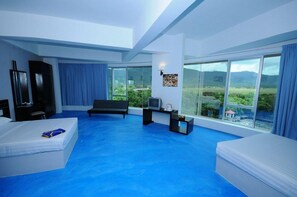 Una camera d'hotel moderna con un letto grande, un divano, una TV e un balcone con vista panoramica.