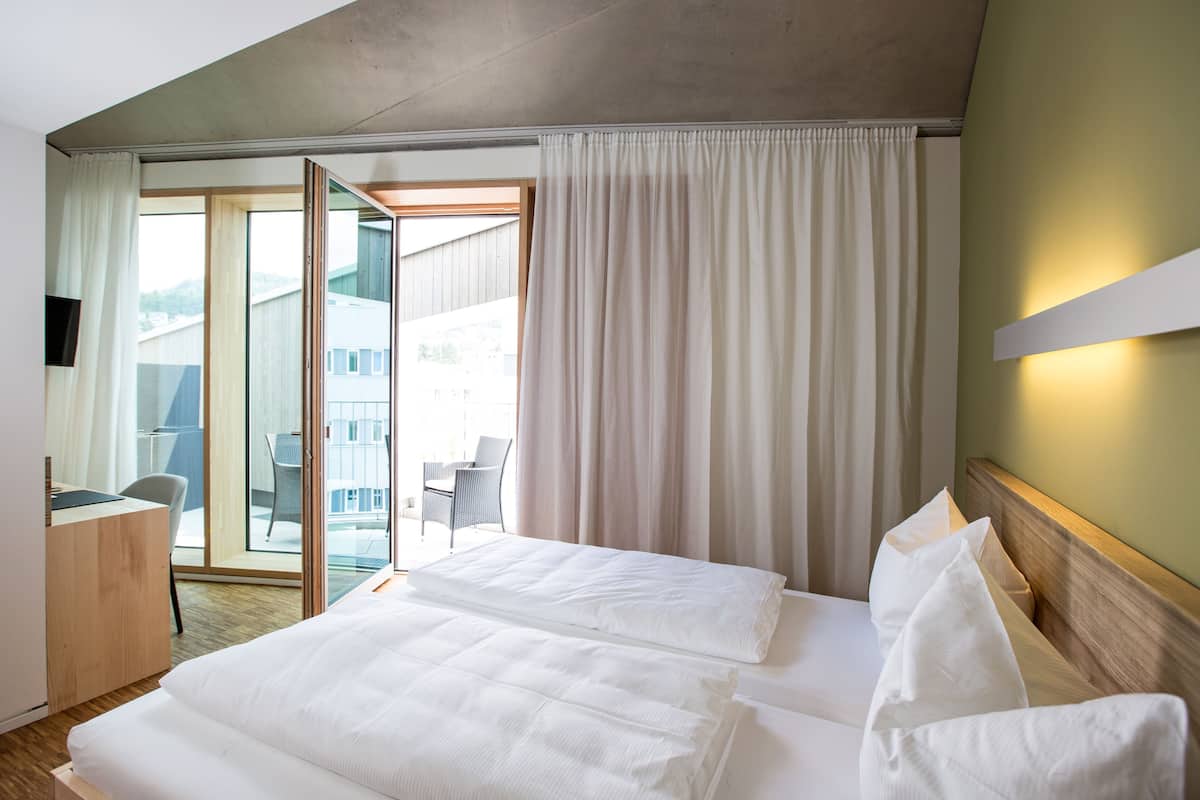 A hotel room with a bed, a desk, and a chair.