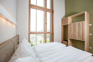 Ein Schlafzimmer mit großem Fenster, Holz-Kopfteil und eingebautem Holzschrank.