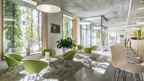Un interior moderno con sillas verdes, una mesa blanca y una planta grande.