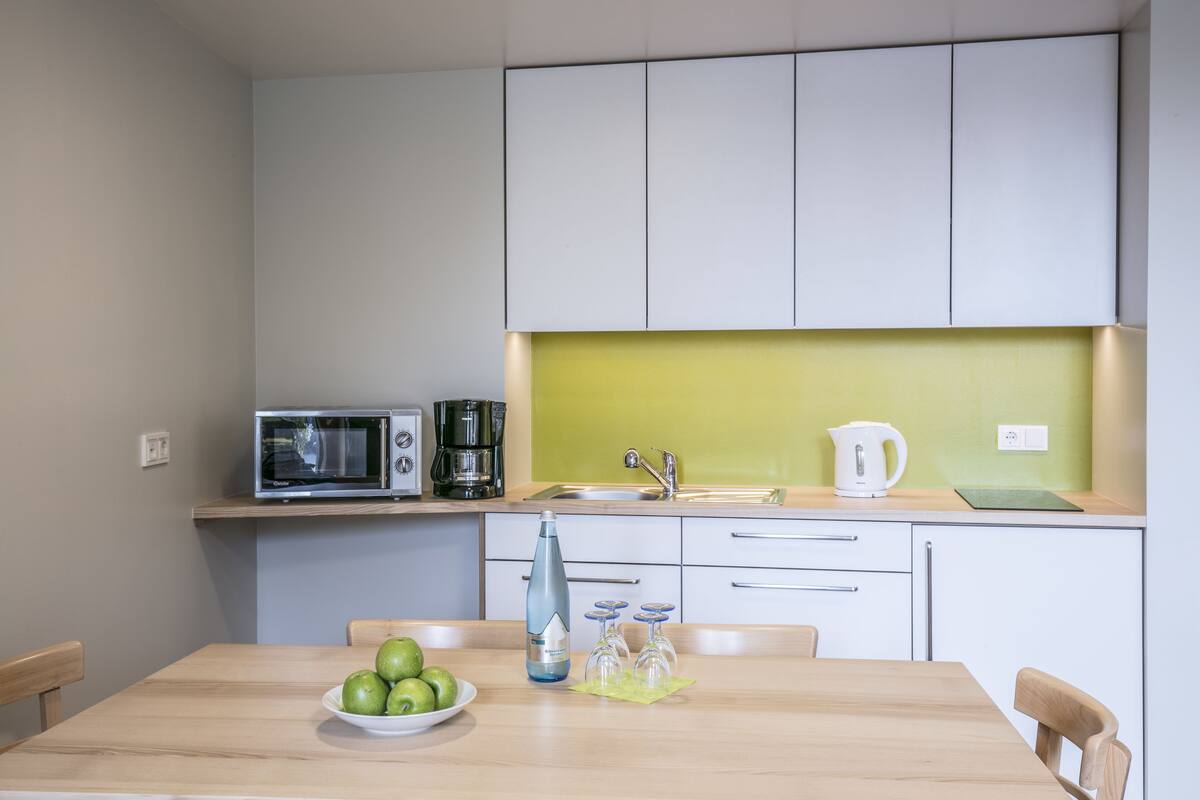 A modern kitchen with a microwave, coffee maker, sink, and a bowl of apples on the counter.