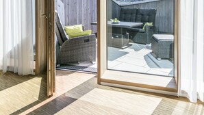 Una habitación moderna con un gran ventanal corredero que da a un área de estar exterior con vistas a la ciudad.