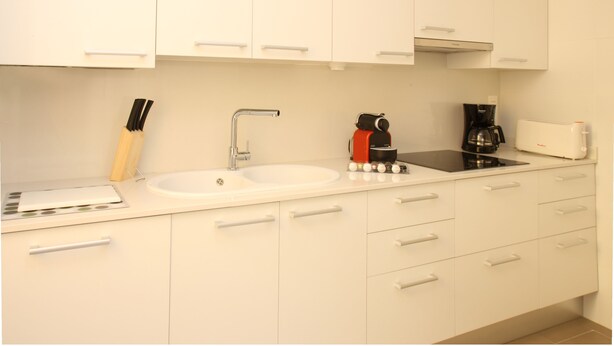 A modern kitchen with white cabinets, a double sink, a coffee maker, and a toaster. - MH Apartments Barcelona (Barcelona)