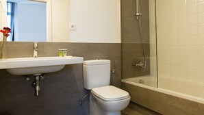 A modern bathroom with a sink, toilet, and glass-enclosed shower. - MH Apartments Barcelona (Barcelona)