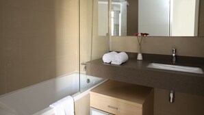 A modern bathroom with a bathtub, a vanity with a sink, and a mirror. - MH Apartments Barcelona (Barcelona)