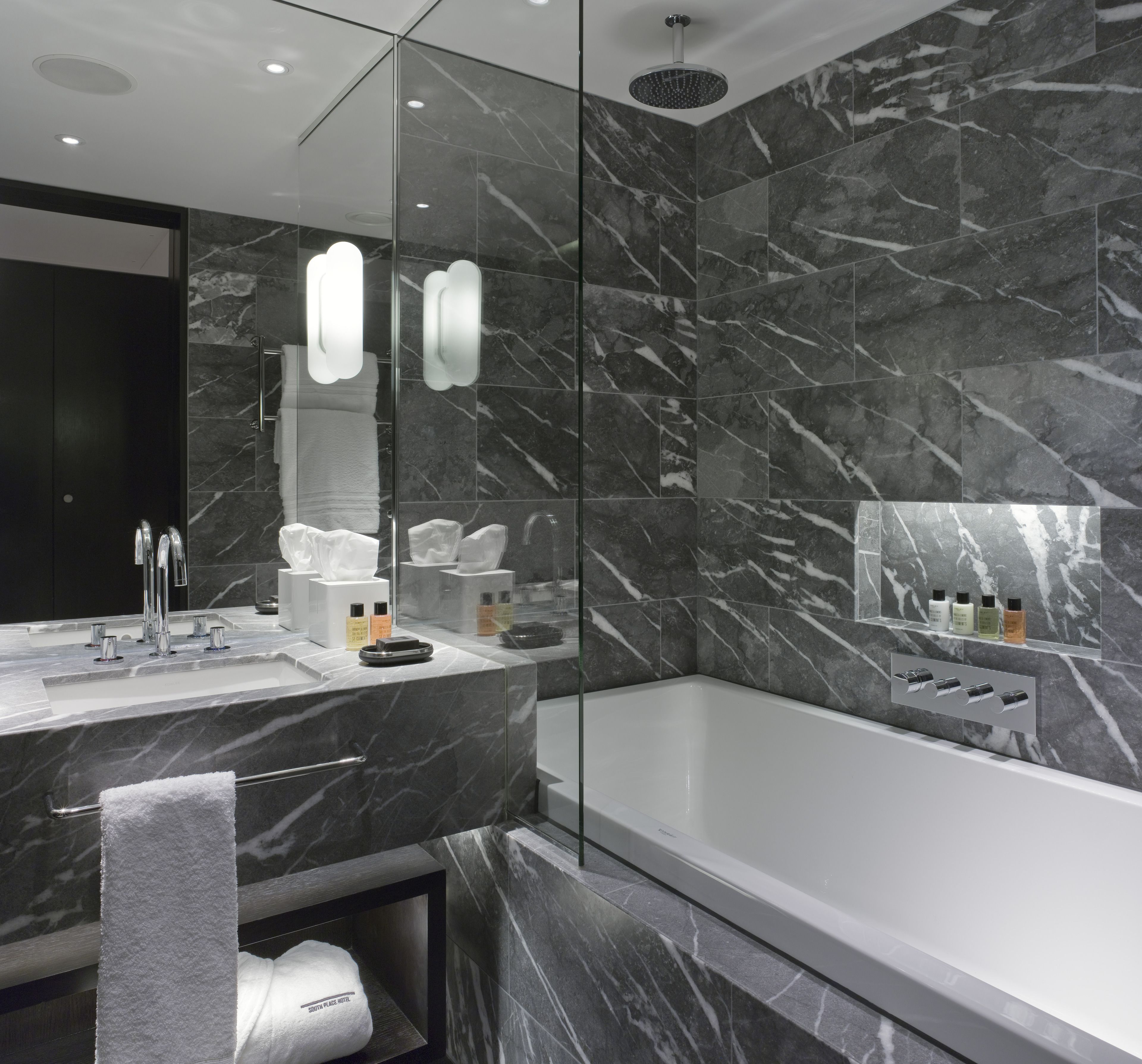 A modern bathroom with a marble sink, a glass-enclosed shower, and a large mirror.