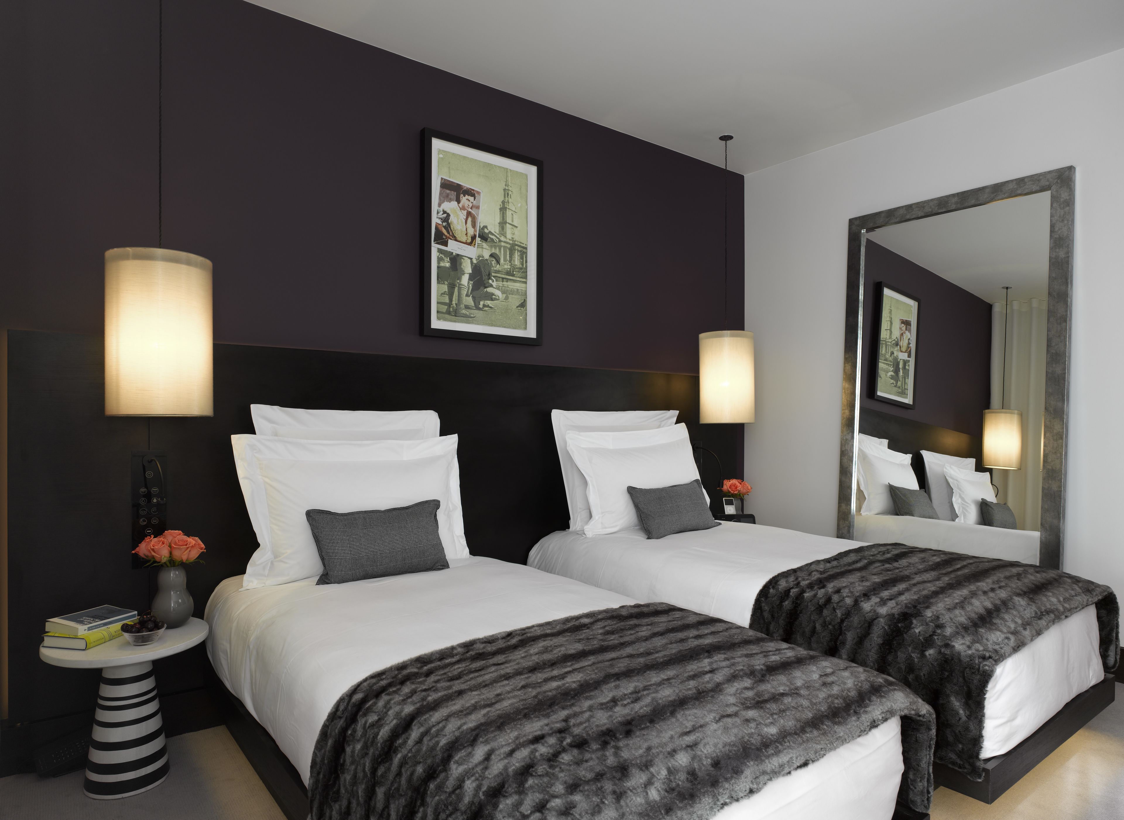 Habitació d'hotel amb dos llits, un mirall gran i un quadre penjat a la paret.