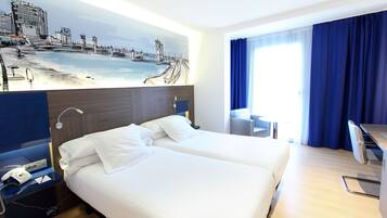 A hotel room with two beds, a desk, a chair, a painting on the wall, and a window with curtains.