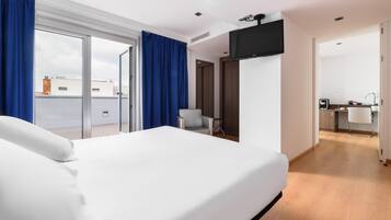 Une chambre d’hôtel moderne dotée d’un grand lit, d’un téléviseur à écran plat fixé au mur et d’une porte-fenêtre coulissante donnant sur un balcon.